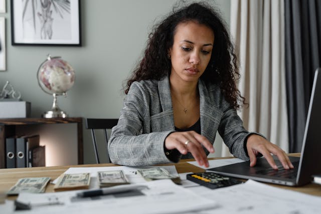 person working at their desk counting money and working spreadsheets