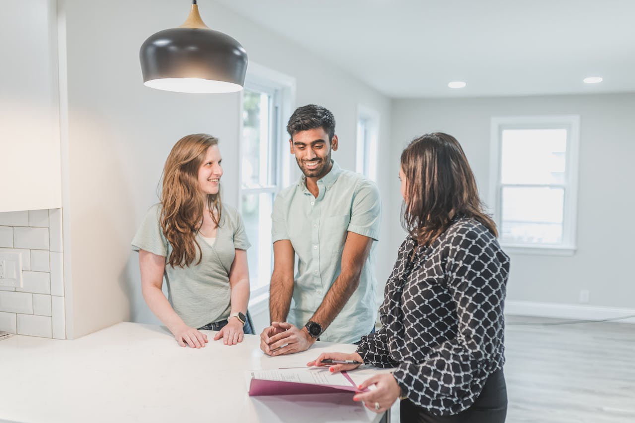 people standing inside empty kitchen, one has papers in front of them