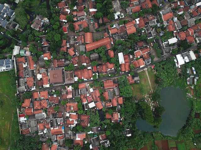 the aerial view of a neighborhood with a pond